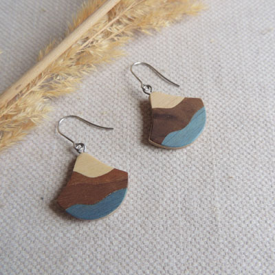 boucle d'oreille en marqueterie bois en forme de ginko avec deux couleurs de bois et du bleu.